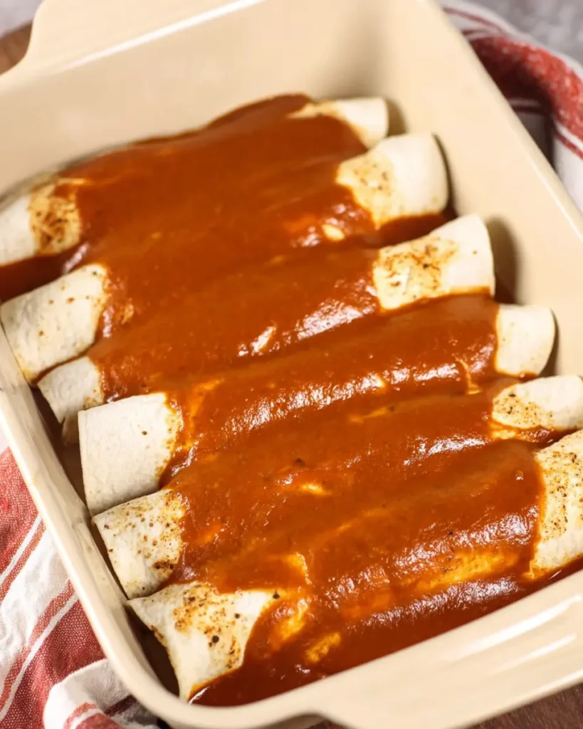 The Best Ground Beef Enchiladas Recipe Everyone Will Love 4 Rolled tortillas topped with enchilada sauce in a baking dish