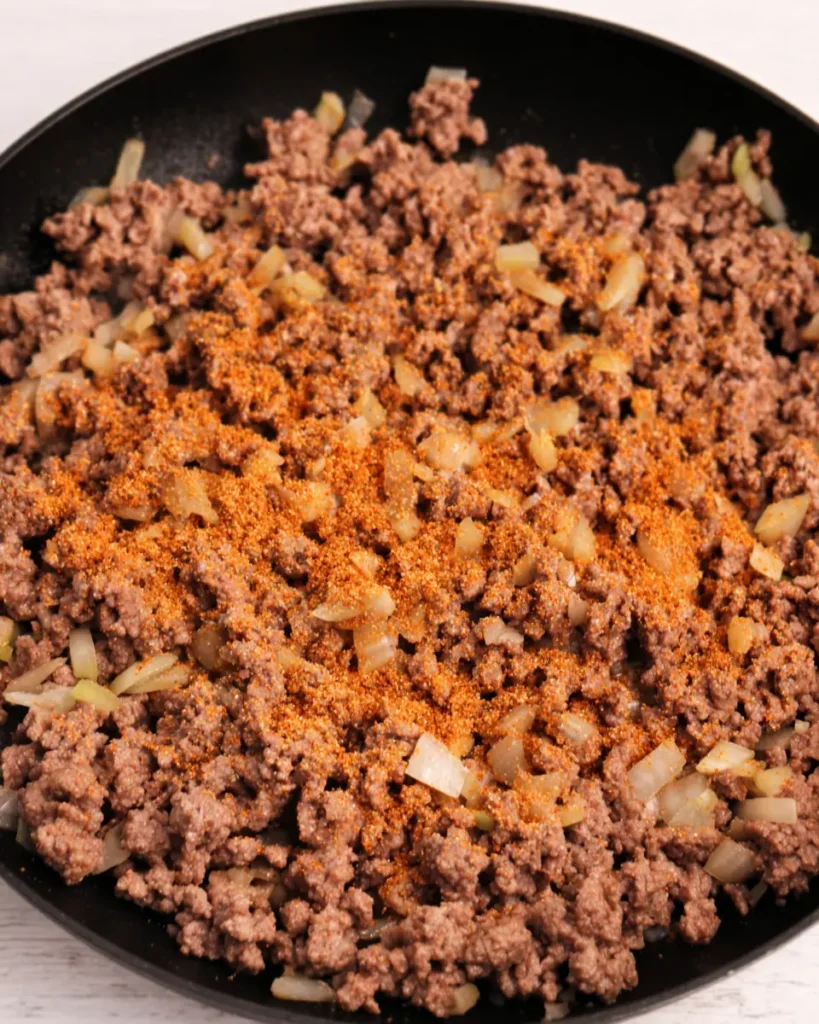 The Best Ground Beef Enchiladas Recipe Everyone Will Love 2 Ground beef and onions cooking with taco seasoning in a skillet